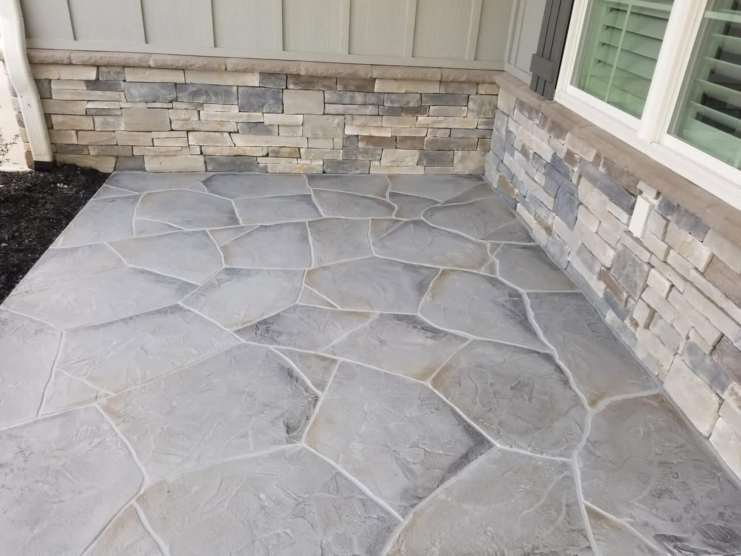 Gray hand-carved flagstone overlay patio beside a stacked stone wall in Greenville SC