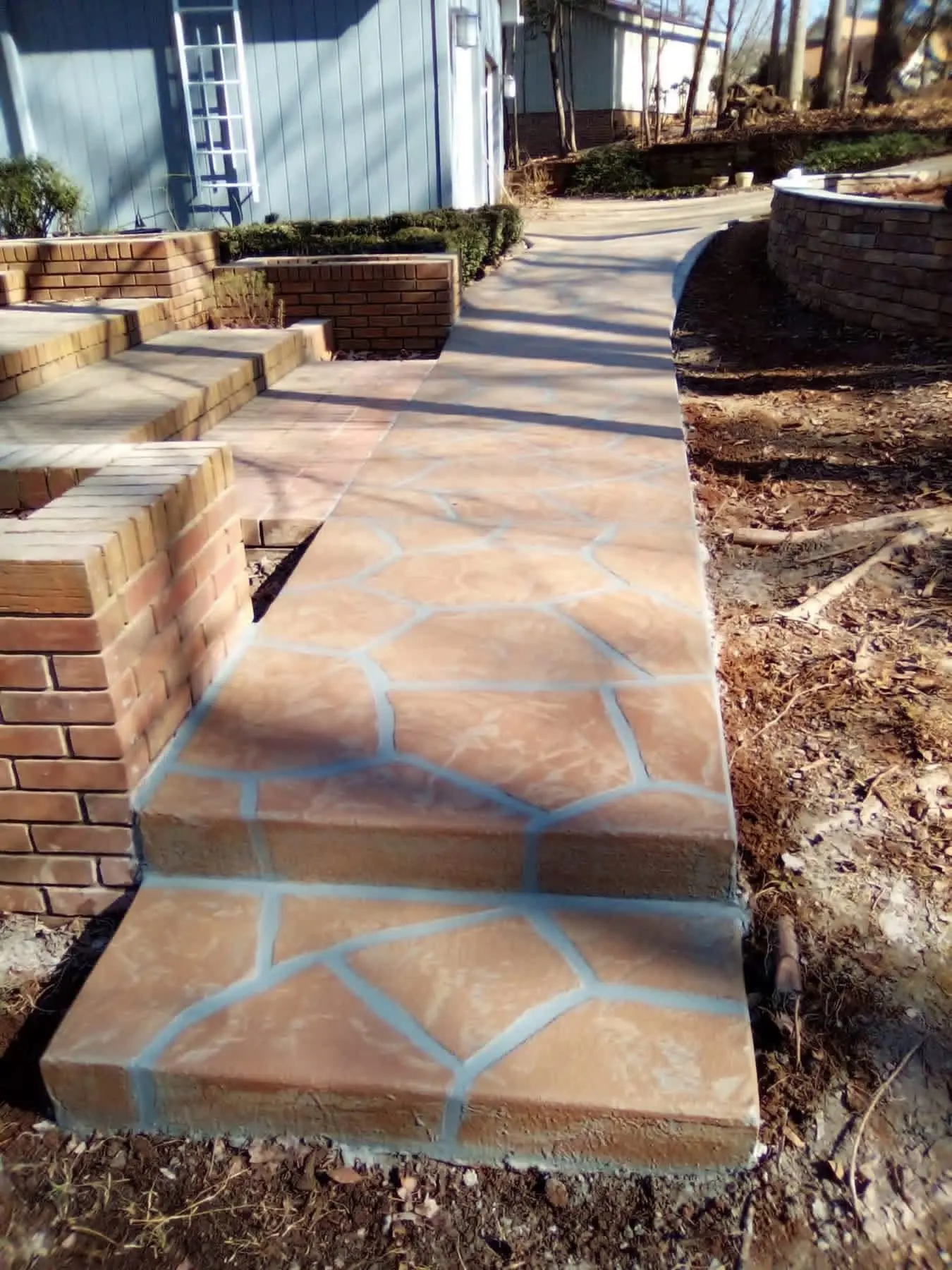 Terracotta stained flagstone walkway and steps beside a brick planter