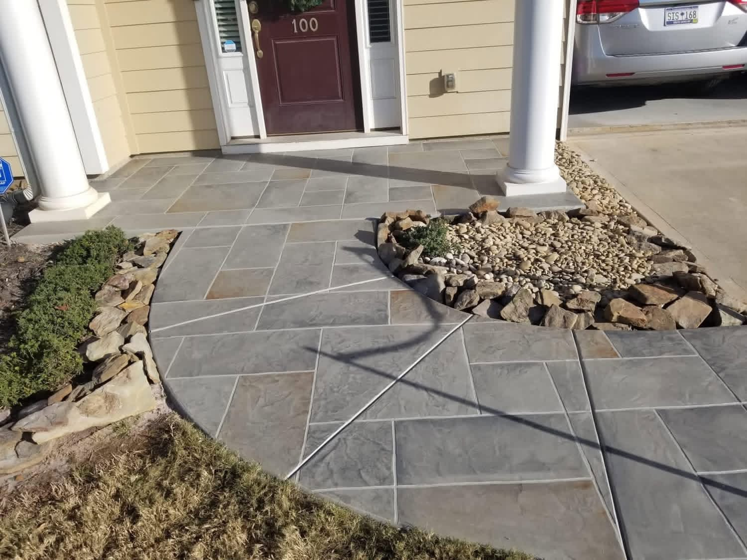 Curved gray stamped concrete walkway and front entry with saw-cut banding